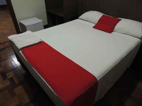a large bed with a red pillow on it at Hotel Gontijo Belo Horizonte - Próximo a Rodoviária e Praça Sete in Belo Horizonte