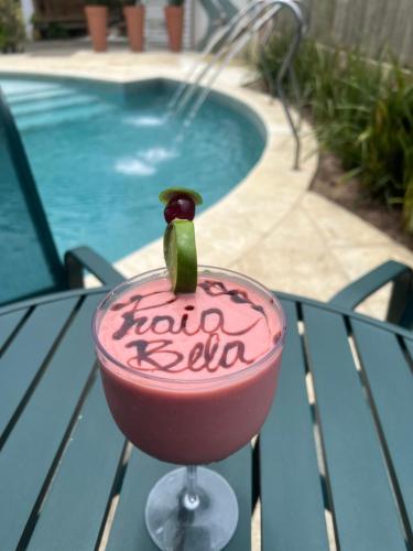 a drink sitting on a table next to a pool at Pousada Praia Bela in Ilhéus