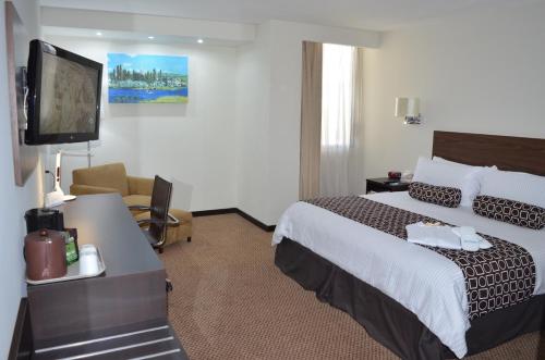 a hotel room with a bed and a flat screen tv at Wyndham Executivo Culiacan in Culiacán
