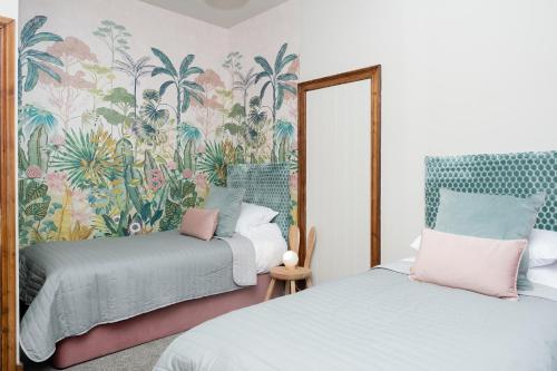 a bedroom with two beds and a floral wallpaper at Watermouth Castle, West Tower Apartment in Ilfracombe
