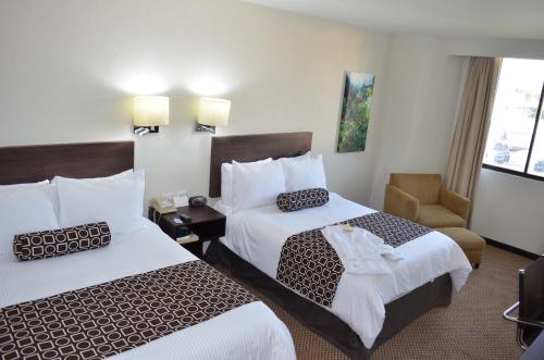a hotel room with two beds and a chair at Wyndham Executivo Culiacan in Culiacán
