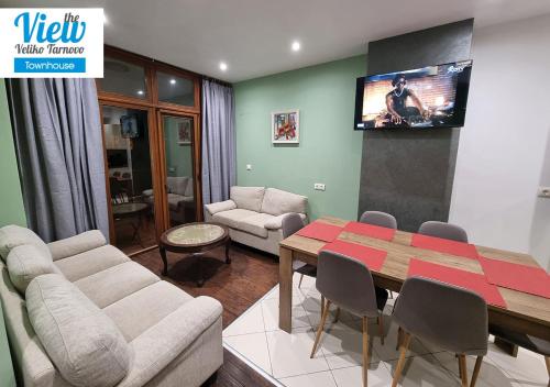 a living room with a table and a tv on the wall at The View Veliko Tarnovo Townhouse in Veliko Tŭrnovo