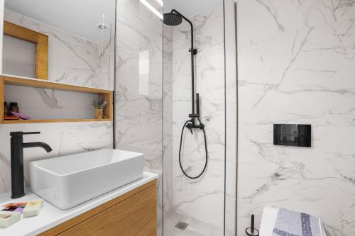 ein Bad mit einer Dusche und einem weißen Waschbecken in der Unterkunft Apartment Arancione in Chania