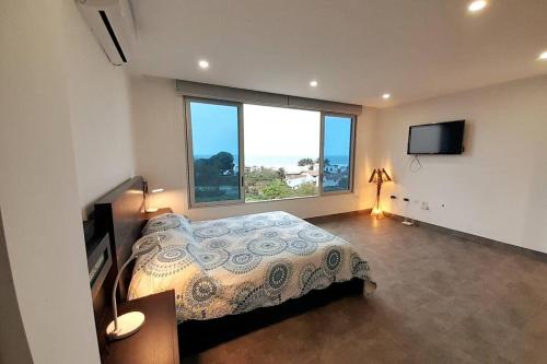 a bedroom with a bed and a large window at Moderna Casa vista al mar San Jose,Ruta Spondylus in La Curia