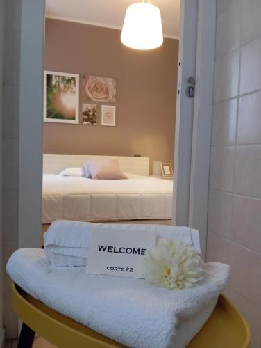 a room with a bed with a welcome sign on a bench at Corte 22 B&b e Appartamenti in Borgomanero