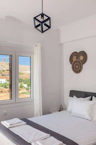 a white bedroom with a bed and a window at Brizet Apartments Sea & Side Sea View in Pollonia