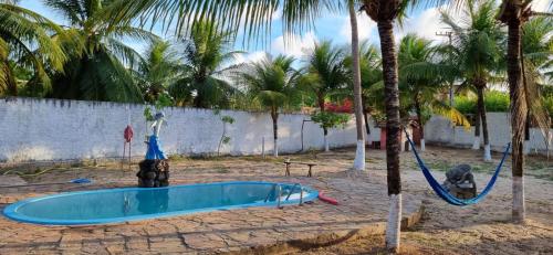 una piscina en un patio con palmeras en Pousada Caseira Varanda da Maya, en Maxaranguape