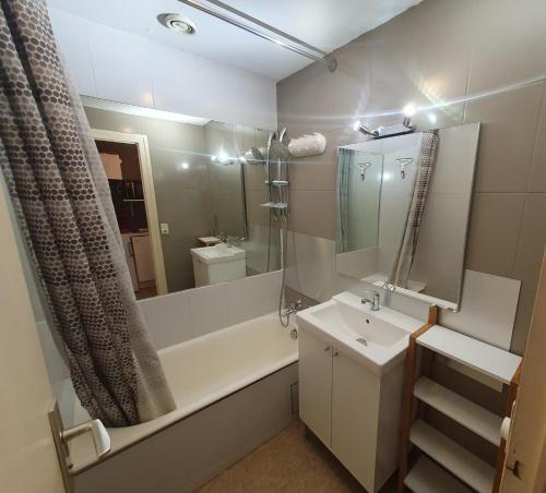 een badkamer met een wastafel, een bad en een spiegel bij Studio du Temple in Aix-les-Bains
