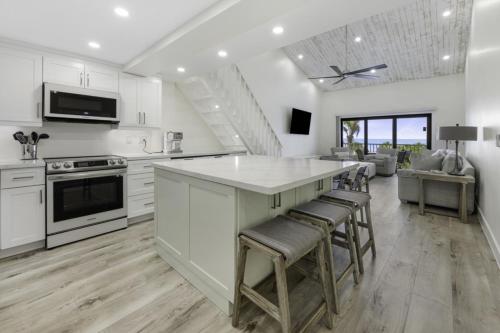 una cocina con armarios blancos y una gran isla con taburetes. en South Seas Beach Villa 2535 home, en Captiva