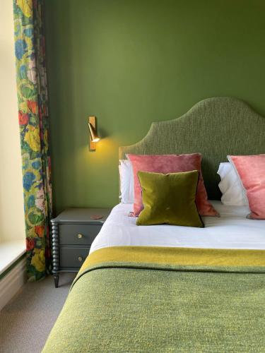 a bedroom with a bed with green walls and pillows at Fellpack House in Keswick