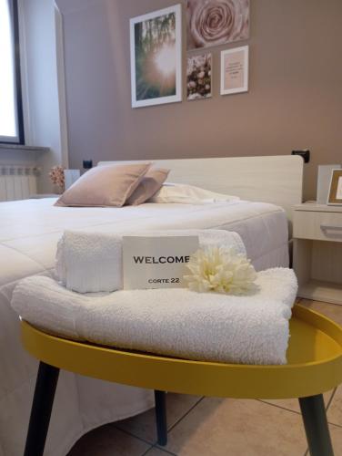 Una cama con una mesa amarilla con toallas. en Corte 22 B&b e Appartamenti en Borgomanero