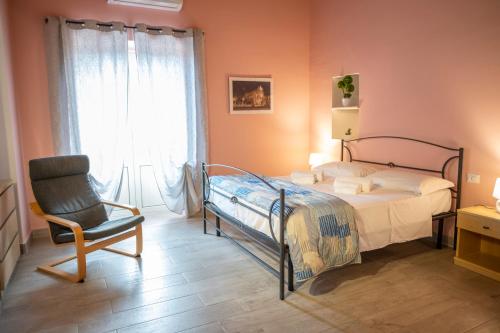 - une chambre avec un lit, une chaise et une fenêtre dans l'établissement "Il Segreto" Vista Panoramica sulle Isole Eolie con Piscina, palestra e WiFi, à Patti