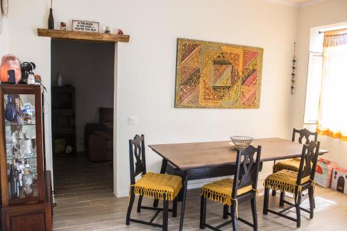 een eettafel met stoelen en een schilderij aan de muur bij Casa da Memória in Angra do Heroísmo