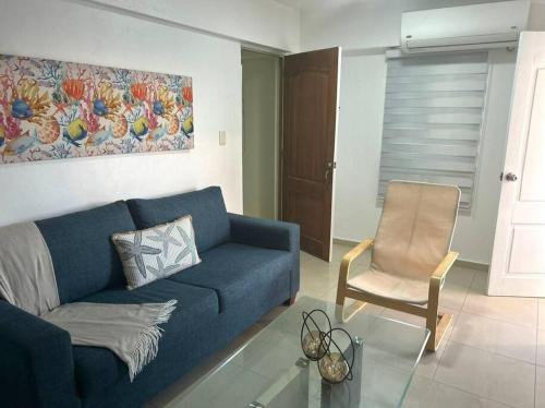 een woonkamer met een blauwe bank en een stoel bij Hermoso Alojamiento Boca Chica in El Higo