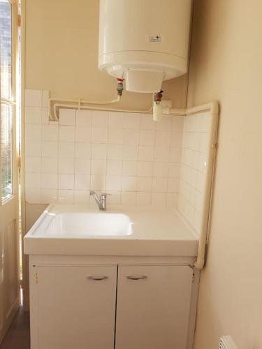 La salle de bains est pourvue d'un lavabo blanc et d'une lampe. dans l'établissement Flat for 2, free car park, 250 m from the seaside., à Étretat