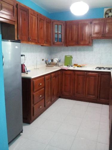 uma cozinha com armários de madeira e um frigorífico de aço inoxidável em Apartment Caribbean Relax em Boca Chica