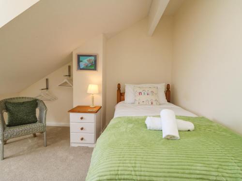 a bedroom with a green bed and a chair at Sea Star in Porthleven