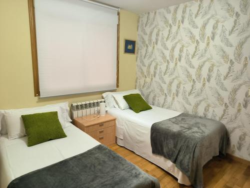 two beds in a room with a window and a wall with at Casa Nano in Sigüeiro