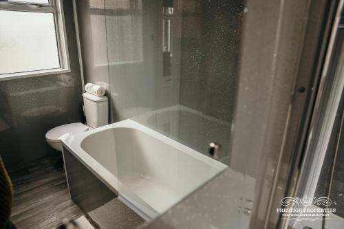 a white bath tub in a bathroom with a toilet at Dover St by Prestige Properties SA in Barrow in Furness