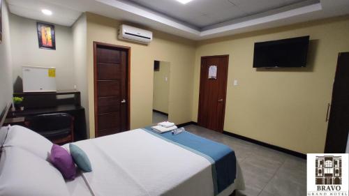 Dormitorio con cama, escritorio y TV en HOTEL BRAVO GRAND HOTEL, en Quevedo
