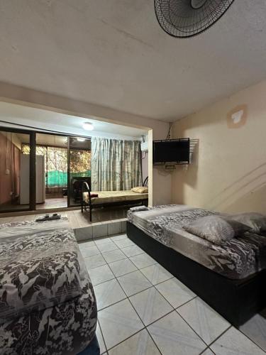 a bedroom with two beds and a flat screen tv at Wide Mouth Frog Conchal in Brasilito
