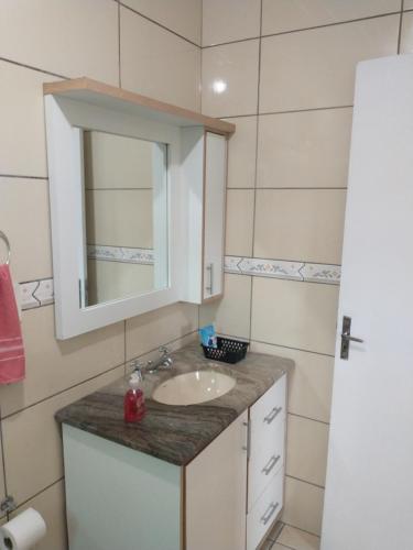 a bathroom with a sink and a mirror at Casa próxima ao shopping Lages e a festa do pinhão in Lages