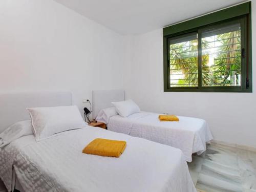 Cette chambre blanche dispose de 2 lits et d'une fenêtre. dans l'établissement Sunflower Appartment, à Nerja