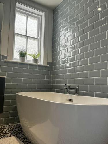 a white tub in a bathroom with a brick wall at The Victorian Townhouse Portrush in Portrush