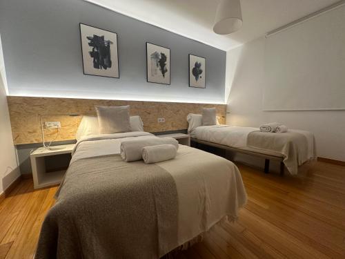 Un dormitorio con dos camas con toallas encima. en HOME GV35 By Oktheway, en Sarria