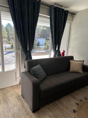 a couch sitting in a living room with windows at Aja apartman Family lux Divčibare in Divčibare