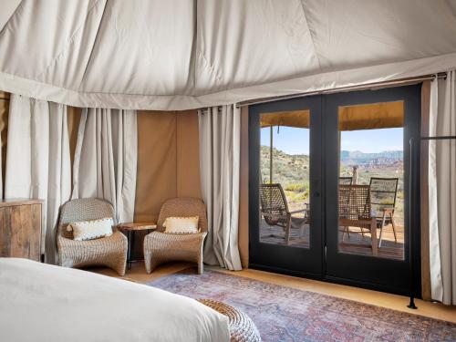 1 Schlafzimmer mit einem Bett und einem Balkon mit Stühlen in der Unterkunft Zion Wildflower in Virgin