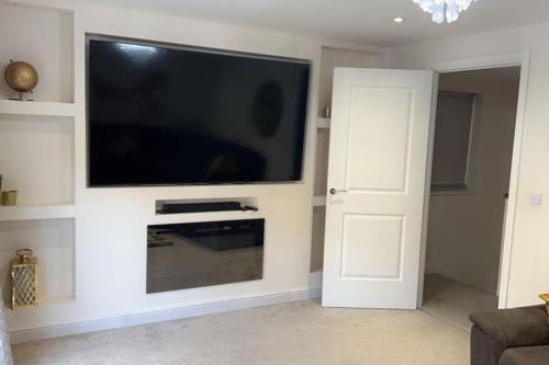 a living room with a flat screen tv on a wall at The American style house in Kent
