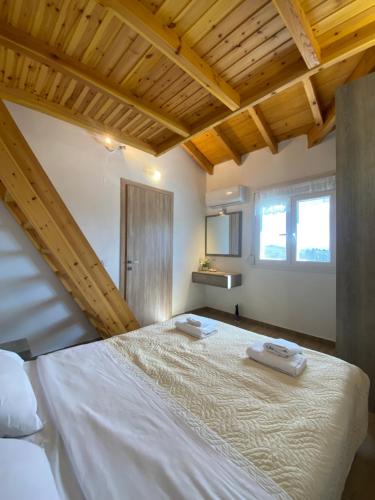 un grande letto bianco in una camera con soffitti in legno di Theo apartment a Marathias