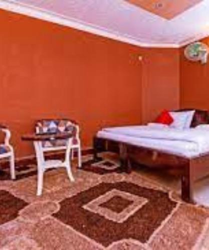 a bedroom with a bed and a table and a chair at Royal Lake View Hotel in Kampala