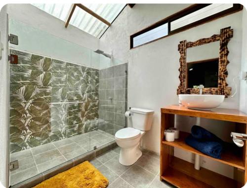 La salle de bains est pourvue de toilettes et d'une douche avec un miroir. dans l'établissement Romantic Private Cabin in the Forest, Bungalows Tulipanes, à San Ramón