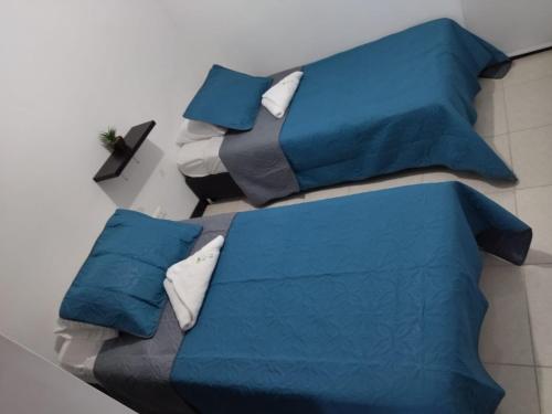 a bed with blue sheets and pillows on it at Lindos Apartamentos Amoblados con piscina in Montenegro