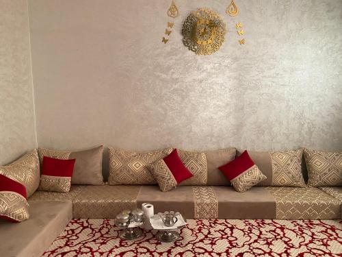 達赫拉的住宿－عقار الشرق الداخلة，客厅配有带红色枕头的棕色沙发