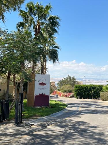 a sign on the side of a road with palm trees at Spacious apartments with Sea view at Samarah Resort in Sowayma