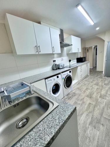 a kitchen with a sink and a washing machine at Full Home in Heywood Street near Cheetham Hill in Manchester