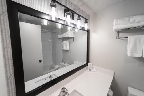 a bathroom with a large mirror over a sink at The Thompson Hotel in Kamloops