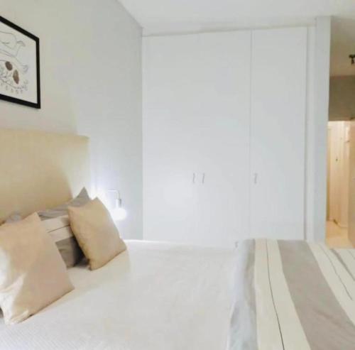 1 dormitorio con 1 cama con paredes y almohadas blancas en ST Chris Villa en Langstrand