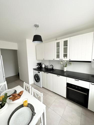 a kitchen with white cabinets and a white table at Jaukūs apartamentai Šilutėje in Šilutė