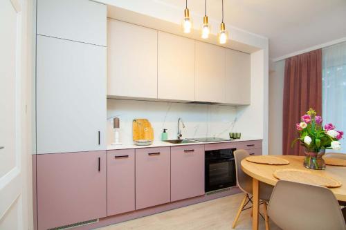 a kitchen with pink cabinets and a wooden table at Apartament Łowca Snów in Chełm