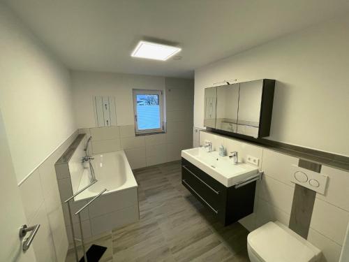 a bathroom with a sink and a tub and a toilet at Moderne Apartments in zentraler Lage in Filderstadt