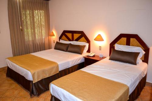 a hotel room with two beds and a telephone at El Tucano Resort & Thermal Spa in Quesada