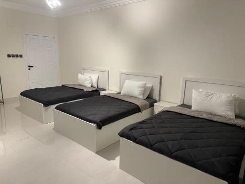 two beds in a white room withskirts at Almadina Laxury Apartemetns in Al Madinah