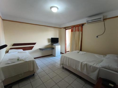 Habitación de hotel con 2 camas y TV en Coroa Bella Praia Hotel, en Coroa Vermelha