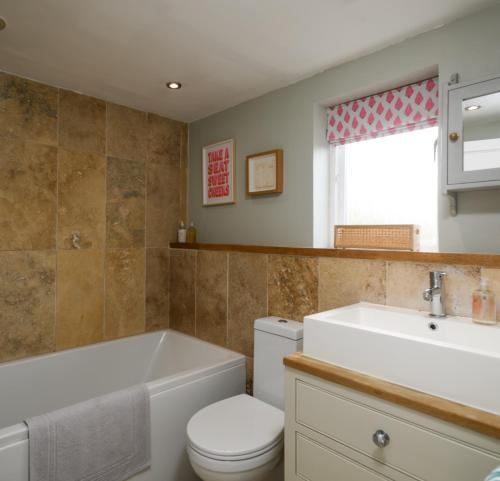 a bathroom with a tub and a toilet and a sink at Charming Barn Retreat Near Pewsey & Woodborough in Woodborough