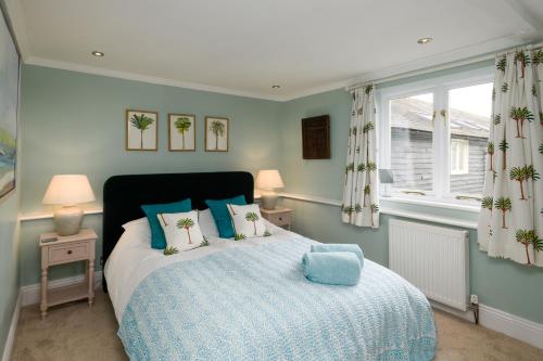 a bedroom with a bed with blue pillows and a window at Charming Barn Retreat Near Pewsey & Woodborough in Woodborough