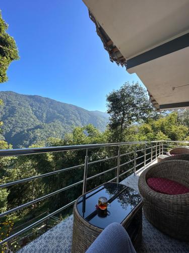 a balcony with a table and chairs and mountains at Majestic Zen Farmstay in Darjeeling